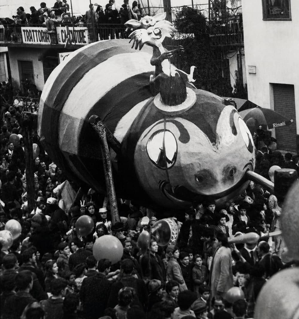 Ein riesiger Pappmaché-Festwagen überragt die Menge in der Dorfstraße, Schwarz-Weiß-Fotografie aus den frühen Jahren des Carnevale